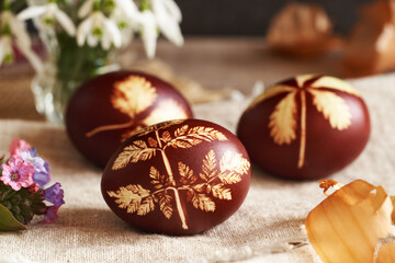 Close up of brown Easter egg dyed with onion peels with a pattern of fresh leaves