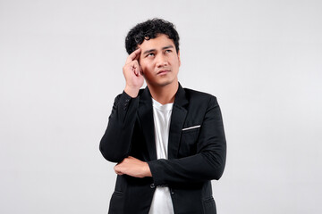Asian man in black blazer and white t-shirt touching temple, looking up with a thoughtful expression. Isolated on white background.