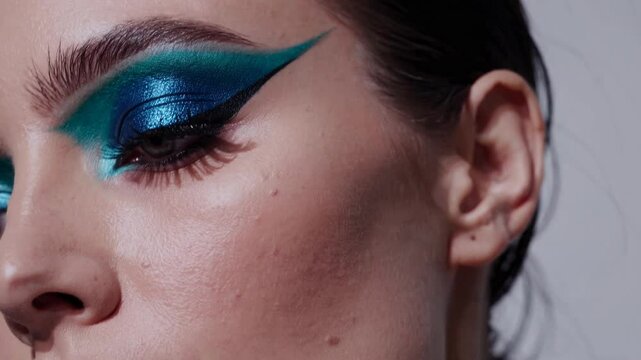Close up video showcasing bold blue and teal eye makeup, emphasizing dramatic eyeliner and detailed artistry on a model