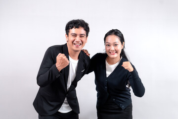 Asian man and woman smiling confidently while raising fists, expressing success and motivation. They look excited and determined, symbolizing teamwork, achievement, and confidence.