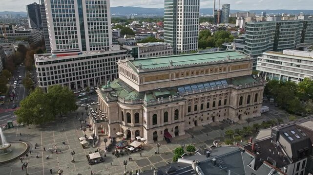 Aerial drone view of Alte Oper in front of Opernplatz, Frankfurt, Germany, showcasing the historic opera house surrounded by modern skyscrapers and urban architecture.