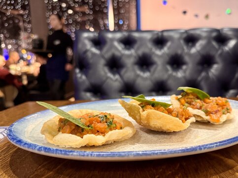 Raw salmon tartare, trout tartare. Delicious raw tuna tartare or sashimi in a white plate on a wooden table in a seafood restaurant. Close-up