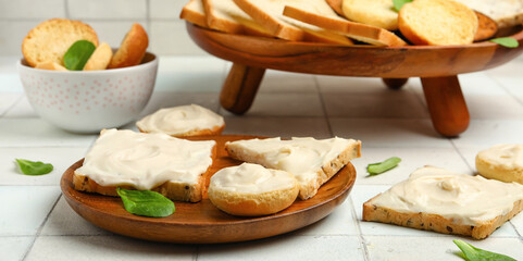 Plate of tasty toasts with cream cheese on white tile background