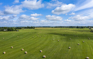 Summer landscape in the countryside of Latvia. Meadow with rolls of hay in Latgale.