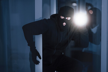 Time For Crime. Cautious burglar looking and peeping into building through window or glass door...
