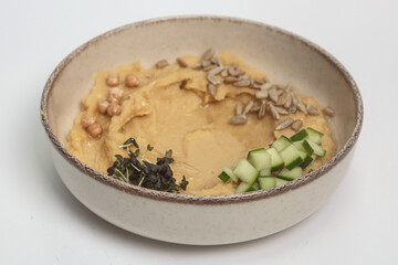 The image shows a bowl filled with a creamy, pale yellow hummus. 