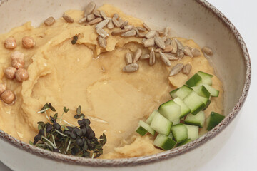 The image shows a bowl filled with a creamy, pale yellow hummus. 