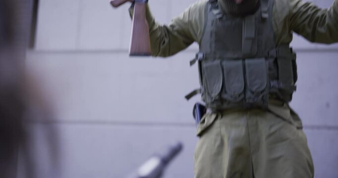 Person with gun pointing it at masked guard who pees in pants and looks scared - tilt shot