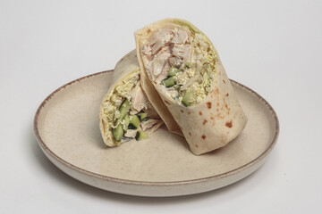The image shows a halved wrap or burrito on a simple beige plate. 