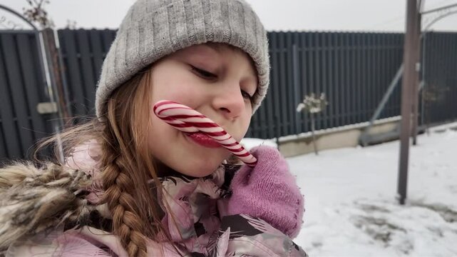A Happy girl eating candy in winter outdoors