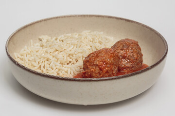 The image shows a simple, yet appetizing dish consisting of plain white rice and two meatballs in a tomato sauce.