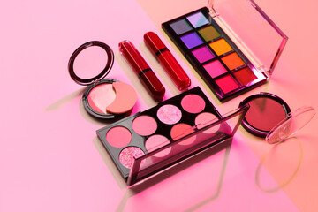 Beautiful palettes of eyeshadows and different decorative cosmetics on pink background