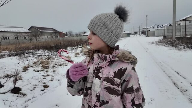 A Happy girl eating candy in winter outdoors