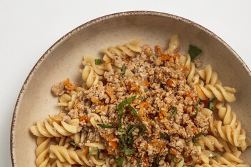 This image shows a bowl of pasta with a hearty meat sauce