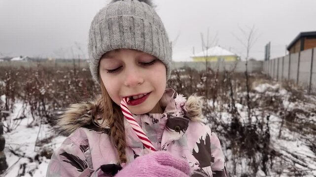 A Happy girl eating candy in winter outdoors