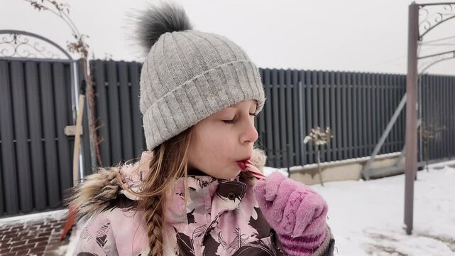 A Happy girl eating candy in winter outdoors