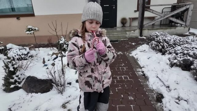 A Happy girl eating candy in winter outdoors