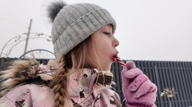 A Happy girl eating candy in winter outdoors