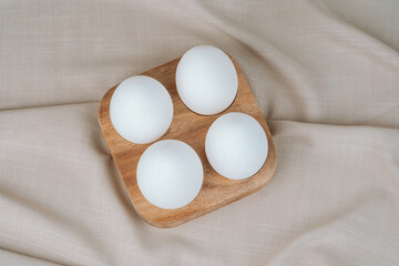 White eggs in a wooden tray on a beige. Natural healthy food and organic farming concept