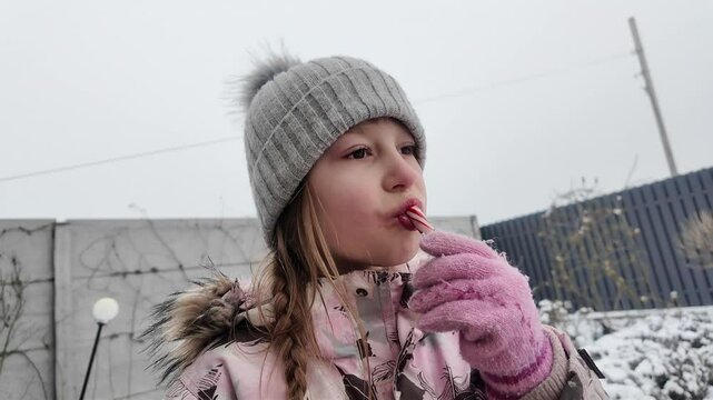 A Happy girl eating candy in winter outdoors