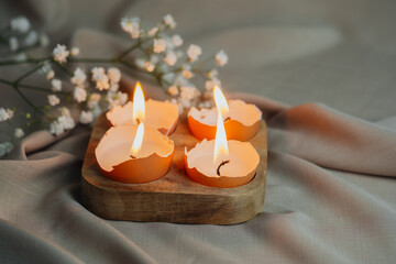 Eggshell burning candles with flowers. Easter background.
