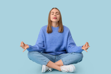 Beautiful young woman meditating on blue background. Zen concept
