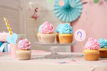 Delicious cupcakes with question mark and decorations on table against pink background. Gender reveal party concept