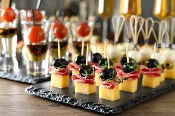 Many different tasty canapes on wooden table, closeup