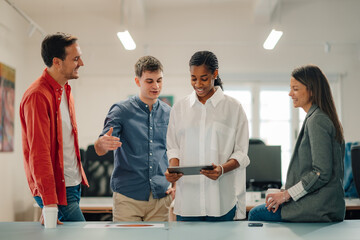 Creative team discussing project on tablet in modern office