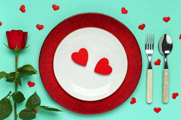 Beautiful table setting with hearts and red rose on turquoise background. Valentine's Day celebration