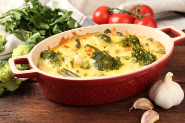 Delicious vegetable casserole and ingredients on wooden table, closeup