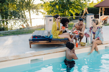 Friends eating watermelon by the poolside during summer vacation