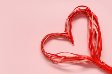 Whip from sex shop in shape of heart on pink background. Valentine's Day celebration