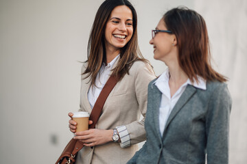 Two businesswomen walking and talking during coffee break