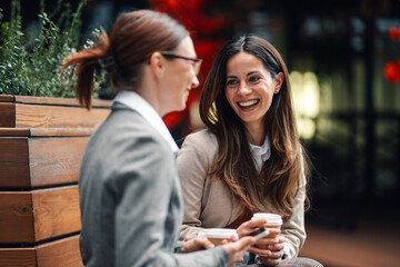 Businesswomen talking and laughing during coffee break outdoors