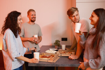 Four friends gathered at a table enjoying pizza, drinks, and friendly conversation
