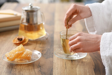 Young woman stirring green tea in kitchen