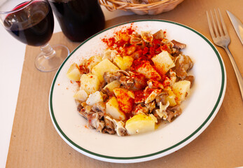 Galician dish of stewed pig's ear with red pepper and potatoes at plate on table