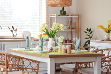 Festive table setting with vase of yellow tulips in modern kitchen