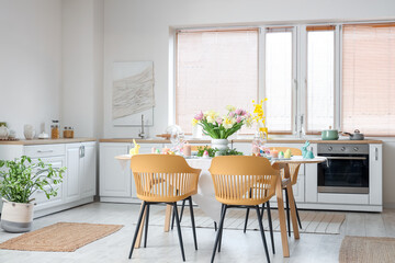 Modern interior of festive decorated kitchen with Easter table setting, window and chairs