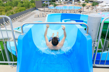 A man is sliding down a blue water slide