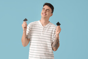 Young man with condoms on blue background