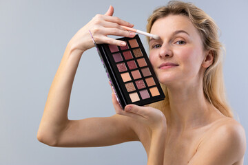 A Woman Applying Makeup From a Palette with Various Shades Featuring a Range of Colors for...