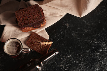 Glass of fresh kvass with slices of bread and wheat on black background