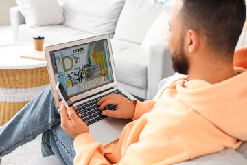 Graphic designer in armchair working with laptop at home