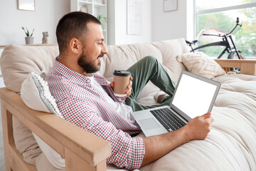 Obraz premium Freelancer lying on sofa and using laptop at home