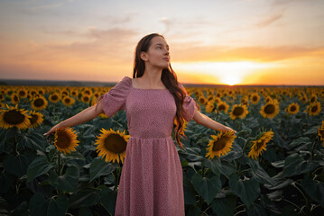 Young Woman in a Sunflower Field at Sunset