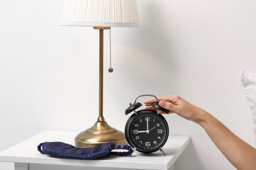Female hand turning off alarm clock in bedroom