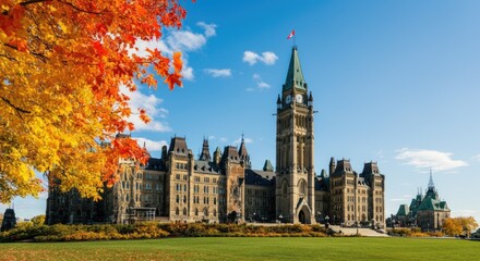 Naklejka premium Canadian parliament building framed by autumn leaves under blue sky