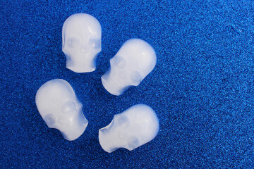 Four skull-shaped ice cubes on a blue background